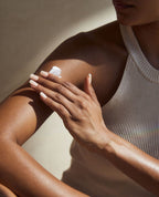 Woman gently massaging body moisturiser into her arm as part of a daily body care routine.