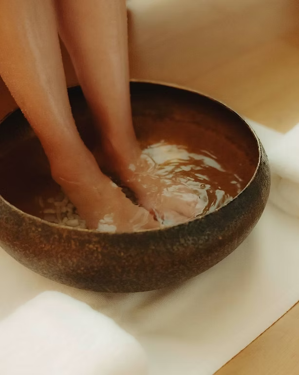Relaxing foot soak preparation with Ginger & Me Happy mineral bath salts in a wooden bowl
