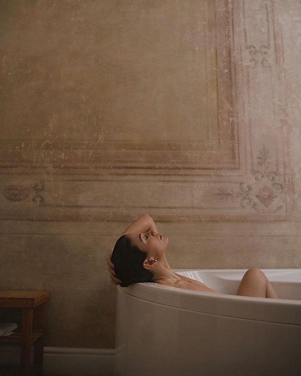 Relaxing bathroom scene with a warm bath and natural tones, reflecting the Ginger & Me bath & body oil care ritual. 