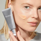 Woman holding Medik8 Crystal Retinal 6 Night Serum 30ml beside her face, with a peach-coloured retinal cream swatch on her cheek.