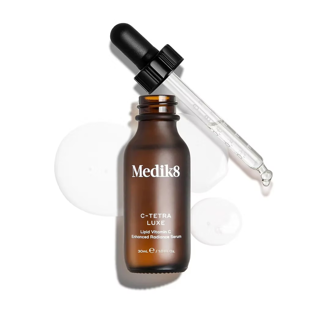 Medik8 C-Tetra Luxe Vitamin C Serum 30ml amber glass bottle with dropper applicator and clear serum droplets on a white background.