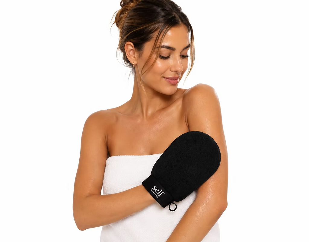 Woman holding the black SELF Tan by O Cosmedics Exfoliating Glove for skin preparation before applying self tan.
