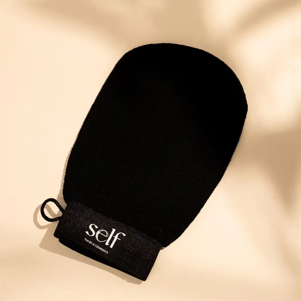 Close-up of black SELF Tan Exfoliating Glove by O Cosmedics showing its rounded shape.