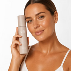 Woman holding SELF Tan by O Cosmedics Hydrating Face Tan Water beside her face, showing a radiant complexion