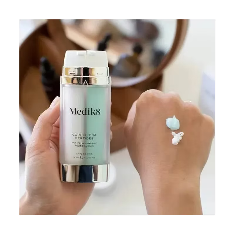 Medik8 Copper PCA Peptides 30ml antioxidant peptide serum held beside a hand showing the turquoise and white serum textures. 