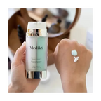Medik8 Copper PCA Peptides 30ml antioxidant peptide serum held beside a hand showing the turquoise and white serum textures. 