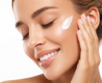 Woman applying white facial moisturiser to her cheek as part of a nourishing skincare routine.