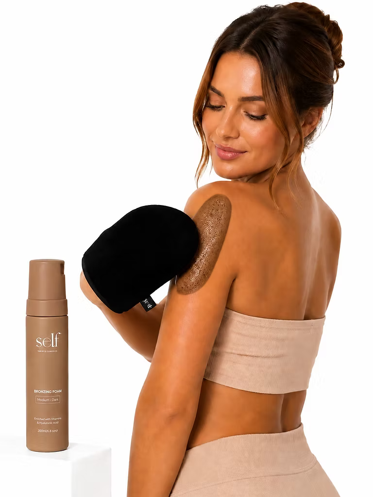 Model holding a black tanning mitt beside SELF Tan by O Cosmedics Dark Self Tan Mousse 200ml