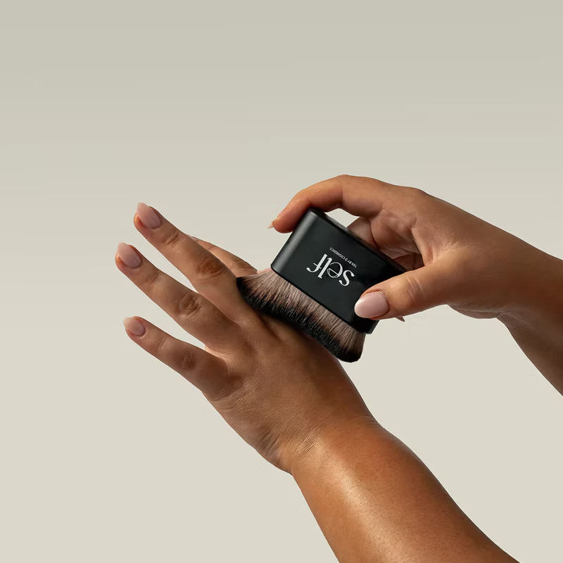 SELF Tan by O Cosmedics Luxury Tanning Brush being used to blend self tanning product evenly onto the hand.