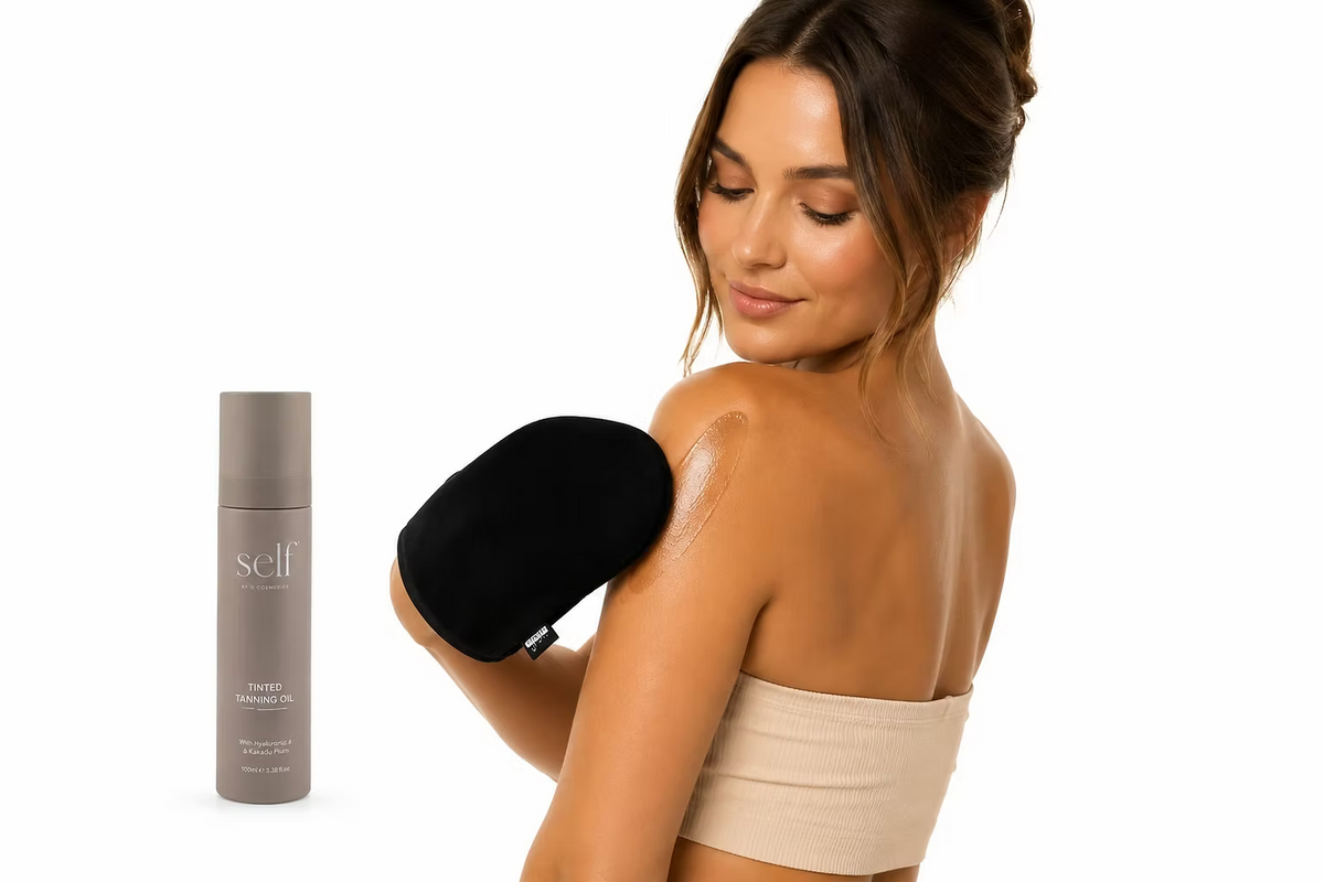 Woman holding SELF Tan by O Cosmedics Tanning Body Oil beside her bronzed shoulder