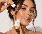 Woman applying Ginger & Me Vitamin Infusion Booster facial serum to her cheek using a dropper.