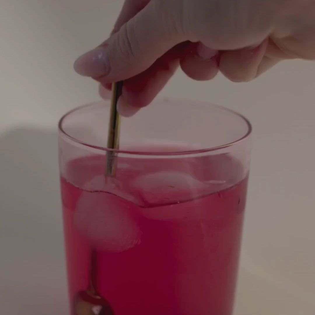 Video demonstrating Frank Simple Collagen Beauty Boost pomegranate collagen supplement being stirred into a glass of water with ice, creating a refreshing pink beauty drink.