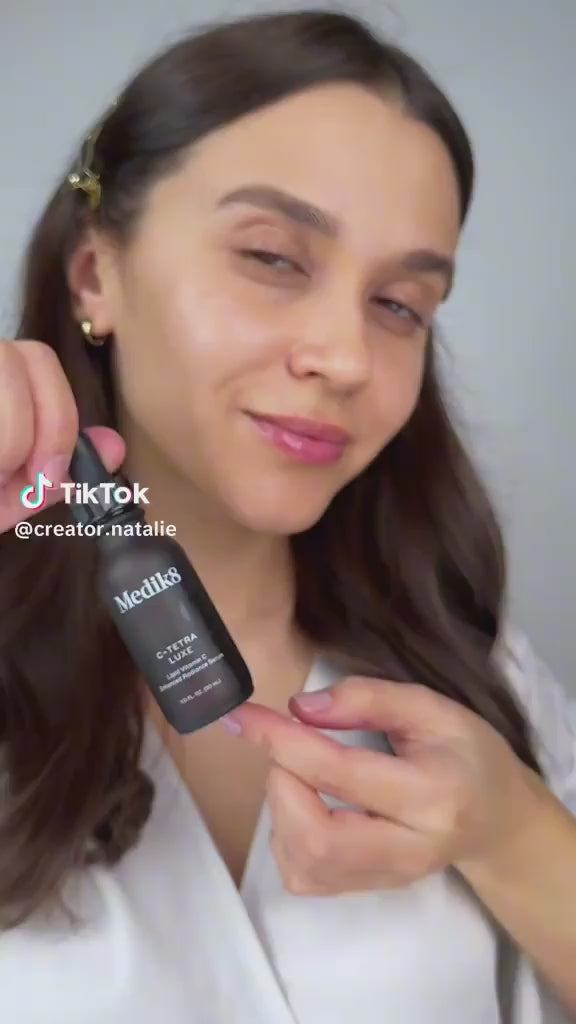 Beauty creator holding Medik8 C-Tetra Luxe Vitamin C Serum 30ml in a skincare demonstration video.